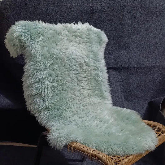 Blue grey sheepskin rug displayed over a woven lounge chair