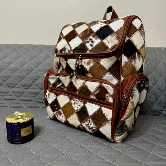 Checkered patterned backpack on a gray couch with a candle beside it