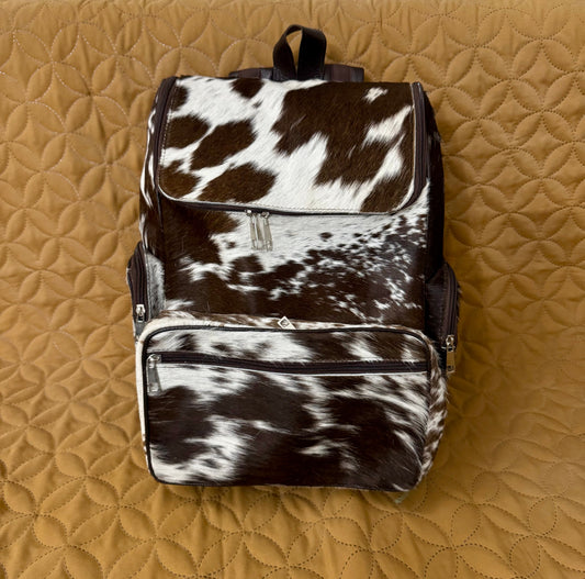 Backpack with cow print pattern on a quilted brown surface