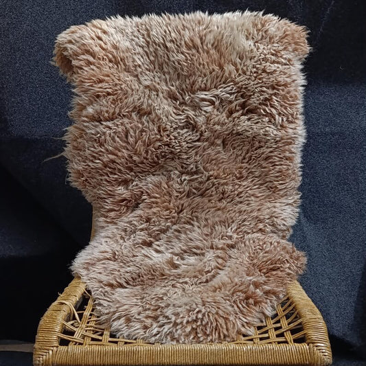 Sandy brown single pelt sheepskin rug displayed on a lounge chair