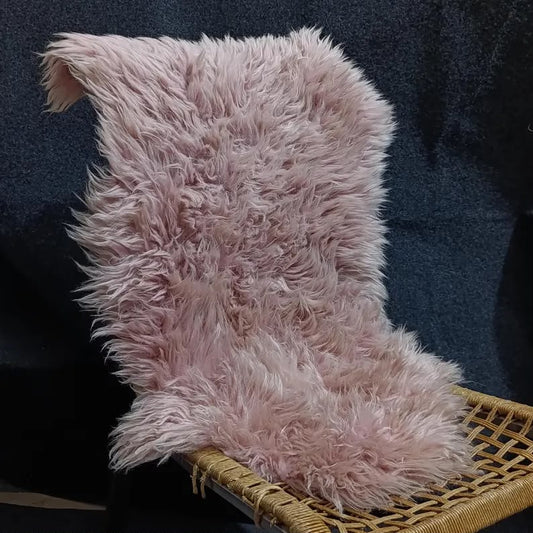 Warm pink sheepskin rug draped over a woven lounge chair