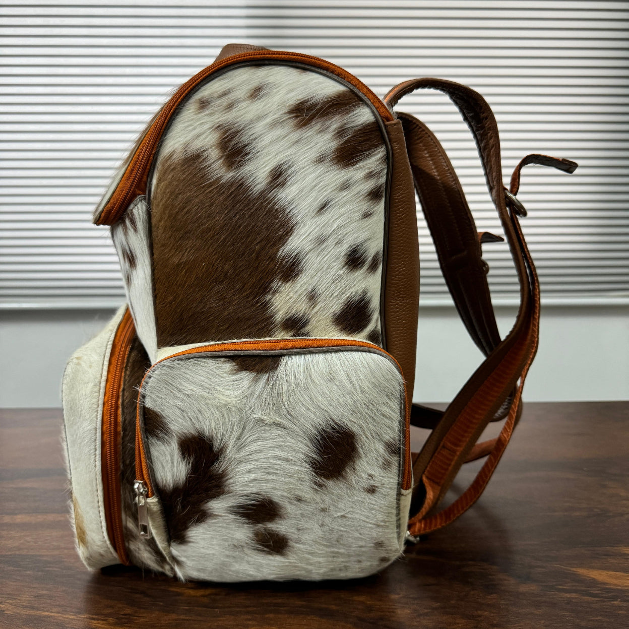 Cowhide diaper backpack side view showing insulated pockets