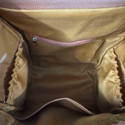 Close-up view of the interior of a handbag, showing a tan satin lining with a zippered pocket, elasticized side compartments, and a pinkish-brown textured leather exterior visible at the top.