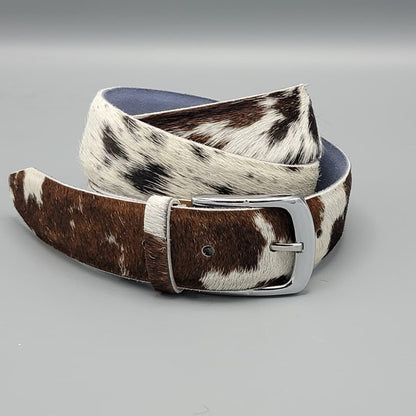 Brown and white cowhide belt with a silver buckle on a gray background