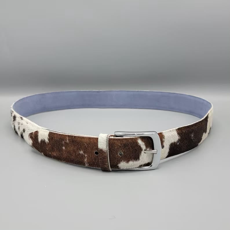 Cowhide belt with a silver buckle on a gray background