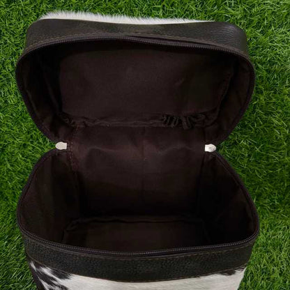 An open black leather zippered case with a cowhide-textured exterior and dark brown fabric lining, photographed on green grass.