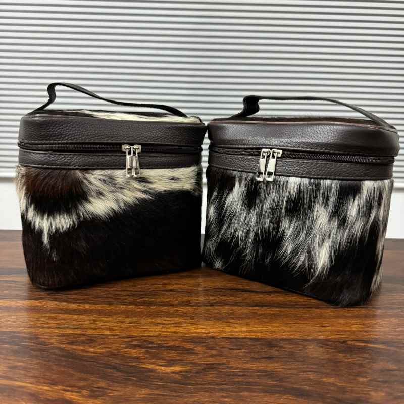 Black and white cowhide cosmetic and toiletry travel bags with leather trim and zipper closure