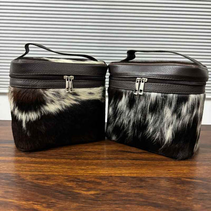 Black and white cowhide cosmetic and toiletry travel bags with leather trim and zipper closure