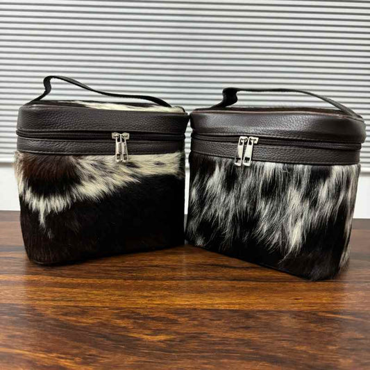 Black and white cowhide cosmetic and toiletry travel bags with leather trim and zipper closure