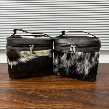 Black and white cowhide cosmetic and toiletry travel bags with leather trim and zipper closure