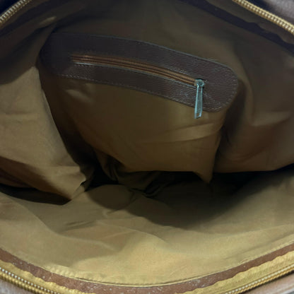 Close-up view of the interior of a brown and tan bag, showing a tan nylon main body, a brown leatherette zippered pocket, and gold-toned metal zippers.