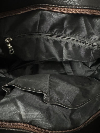 Close-up of the interior of cowhide tote bag, showing a zippered compartment with a silver zipper pull and a pocket with brown zipper trim.