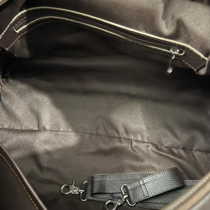 Close-up view of the interior of a dark brown bag, showing a padded zippered pocket with silver-tone zipper pulls and a matching dark brown detachable strap with metal swivel clasps.