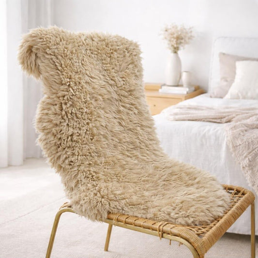 Beige natural sheepskin rug draped over a rattan lounge chair