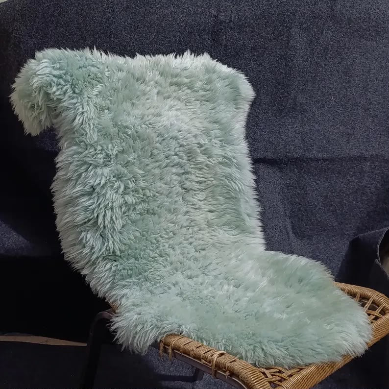Blue grey sheepskin rug displayed over a woven lounge chair