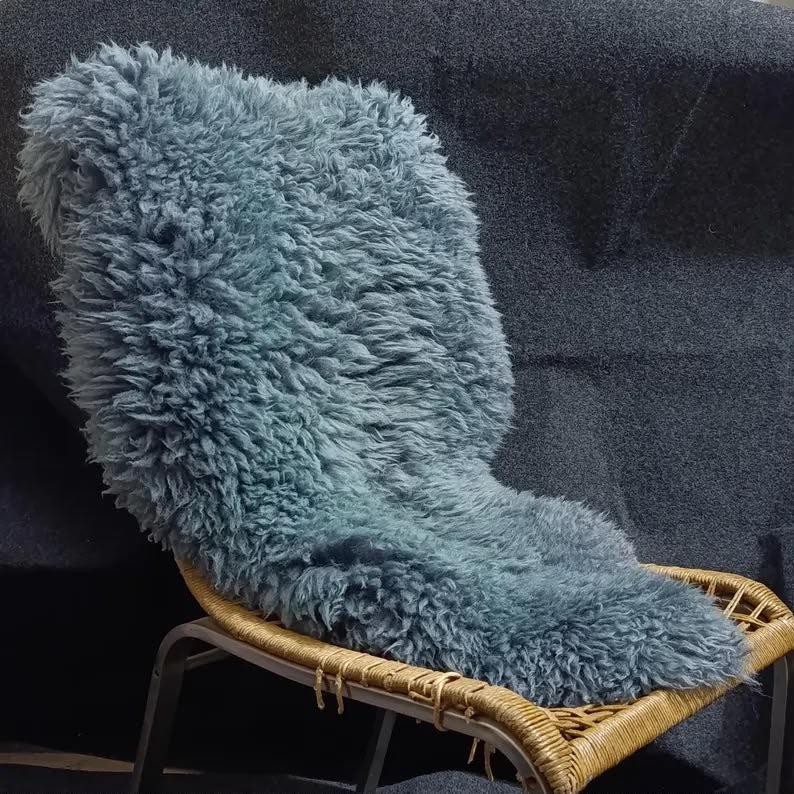 Blue sheepskin rug displayed over a woven lounge chair