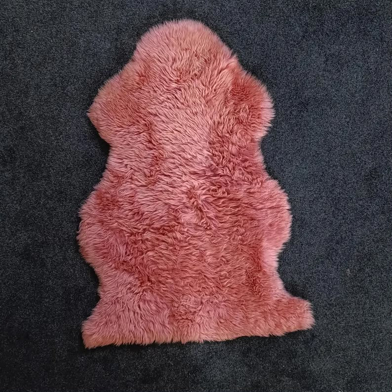 Blush pink sheepskin pelt rug showing its natural shape and wool texture