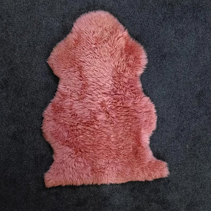 Blush pink sheepskin pelt rug showing its natural shape and wool texture