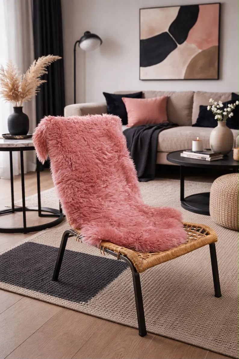 Blush pink sheepskin rug styled over a chair in a modern living room