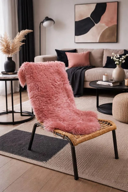 Blush pink sheepskin rug styled over a chair in a modern living room