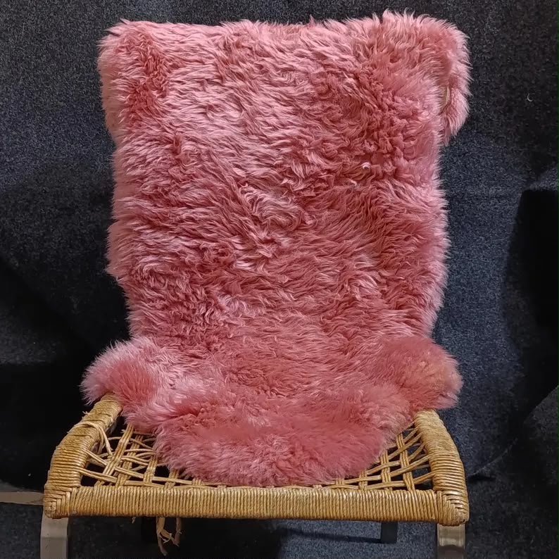Blush pink single pelt sheepskin rug displayed on a woven chair