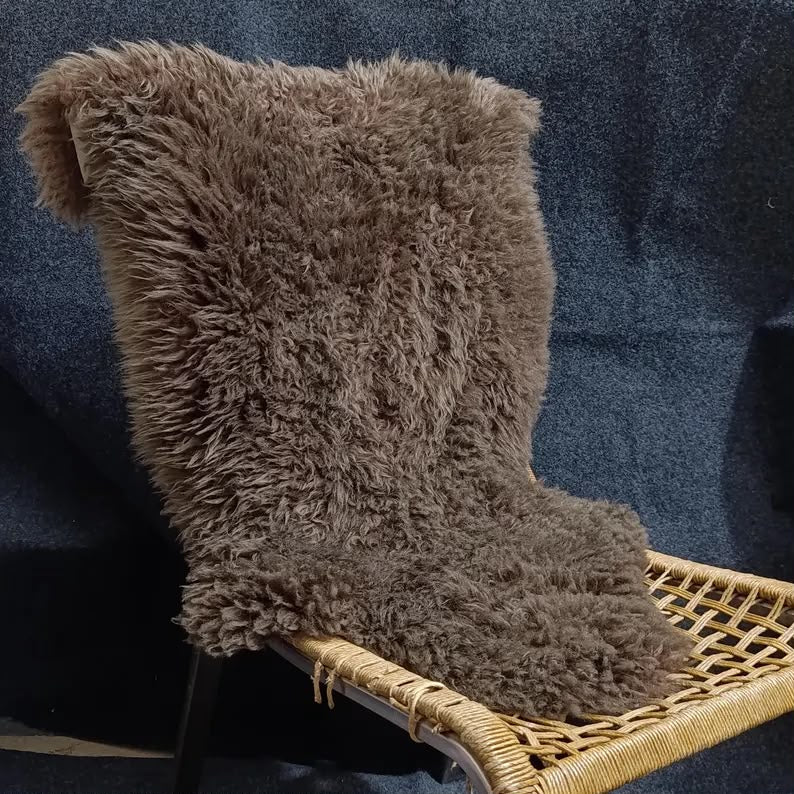 Brown sheepskin pelt rug displayed over a woven chair