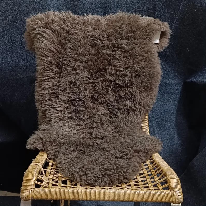 Brown sheepskin rug draped over a woven lounge chair