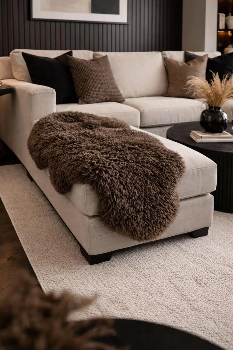 Dark brown sheepskin rug draped over a cream ottoman