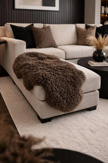 Dark brown sheepskin rug draped over a cream ottoman