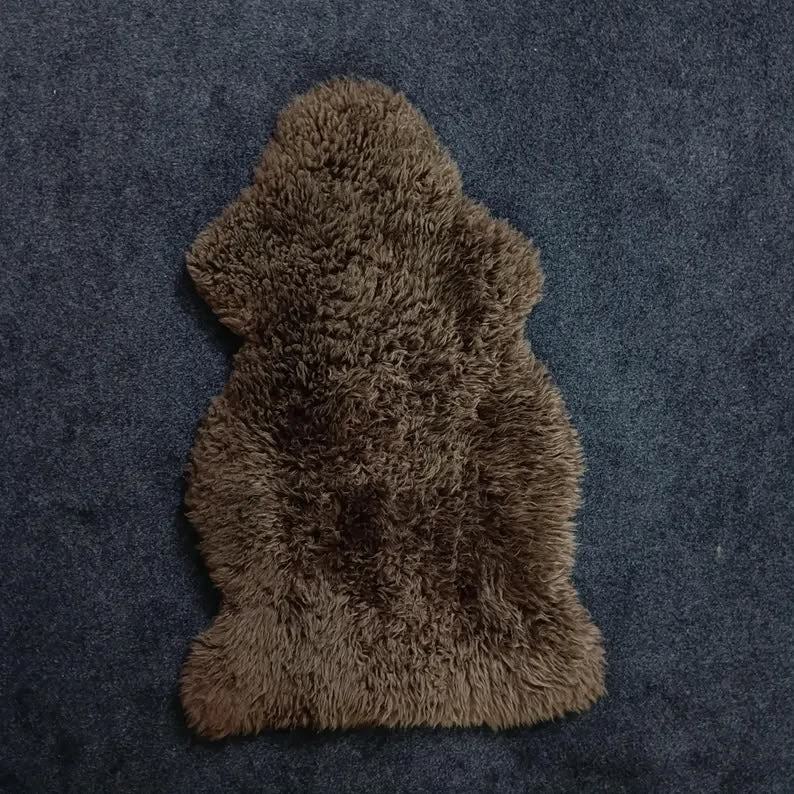 Dark brown single pelt sheepskin rug showing its natural shape and wool texture