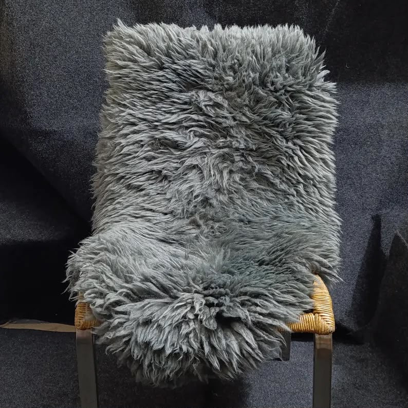 Dark grey sheepskin pelt rug styled over a woven chair