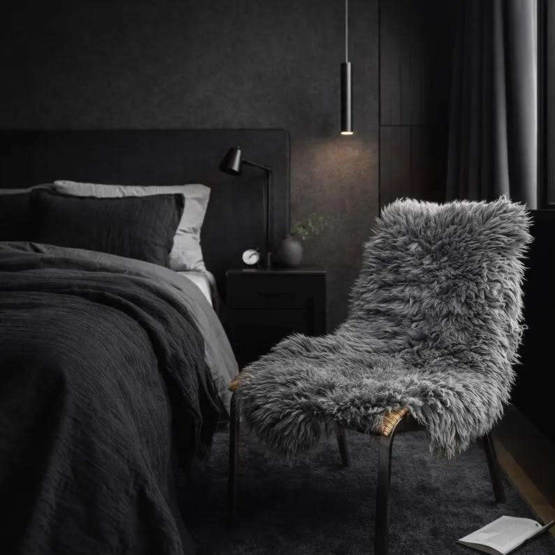 Dark grey sheepskin rug styled on a chair in a modern dark bedroom