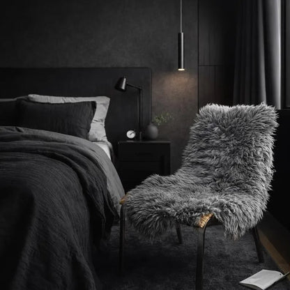 Dark grey sheepskin rug styled on a chair in a modern dark bedroom