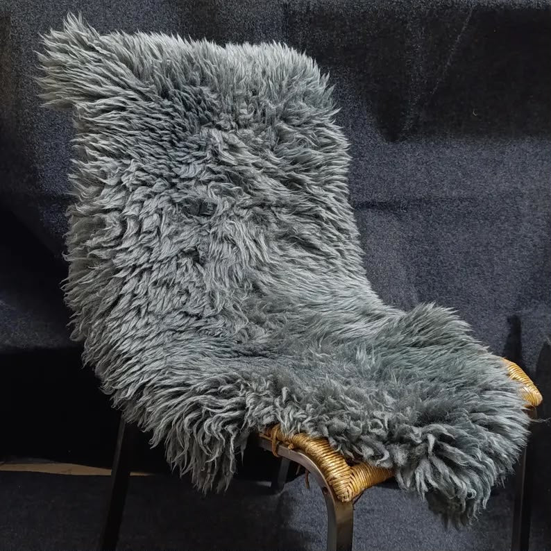 Dark grey sheepskin rug displayed over a woven lounge chair