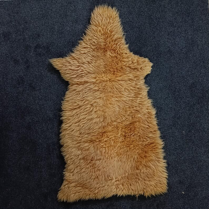 Golden beige sheepskin pelt rug displayed over a woven chair