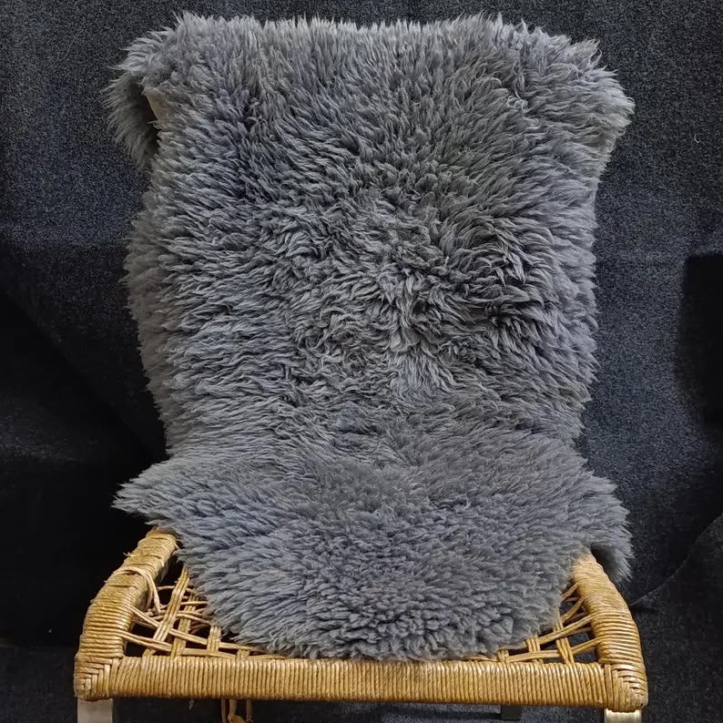 Grey natural sheepskin rug draped over a woven lounge chair