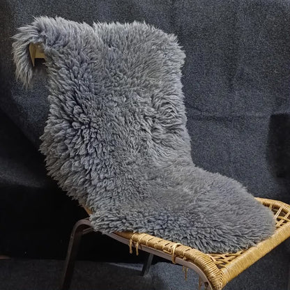 Grey sheepskin pelt rug styled over a woven accent chair