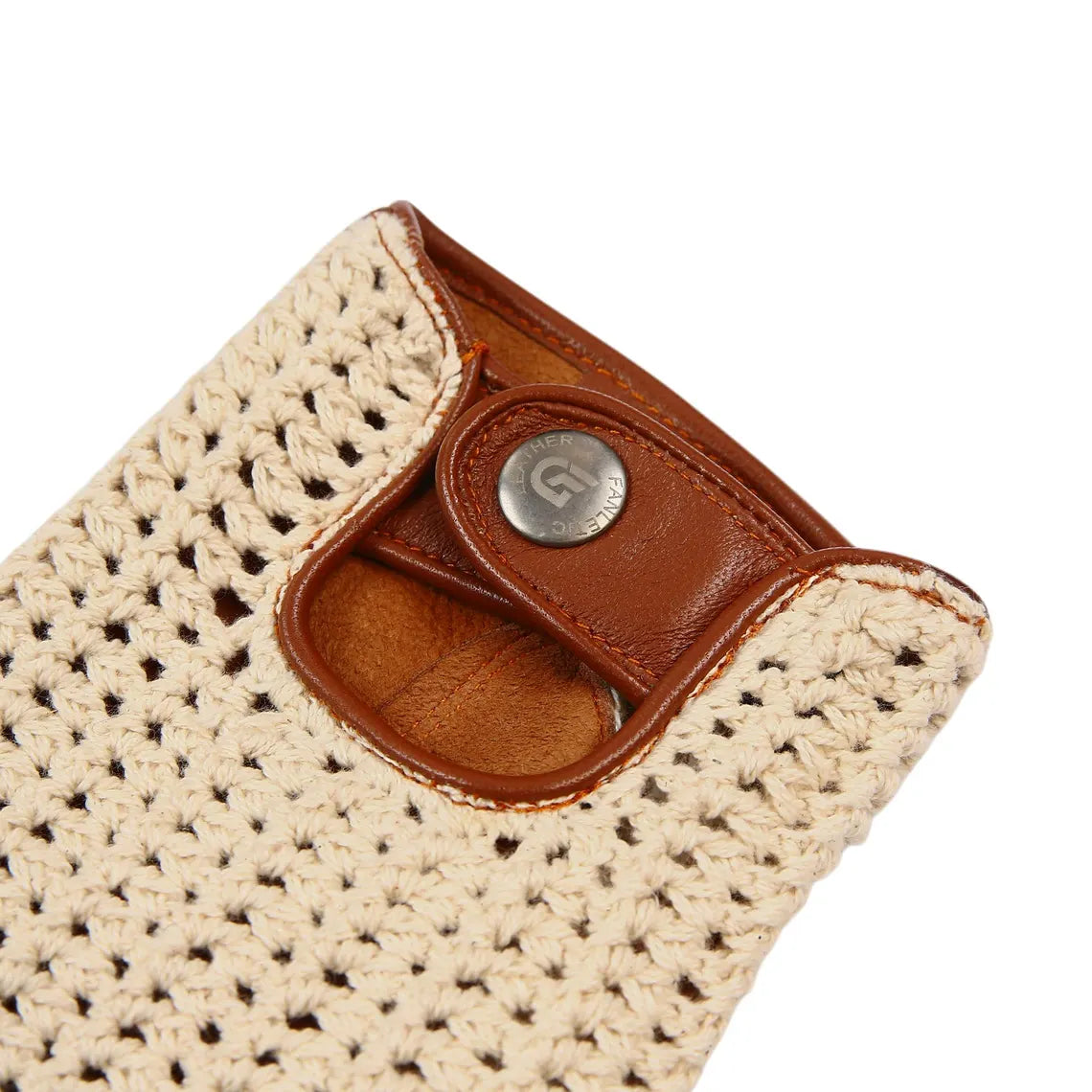 Close-up of a woven beige crochet pouch with a brown leather snap tab and a round silver metal button on a white background.