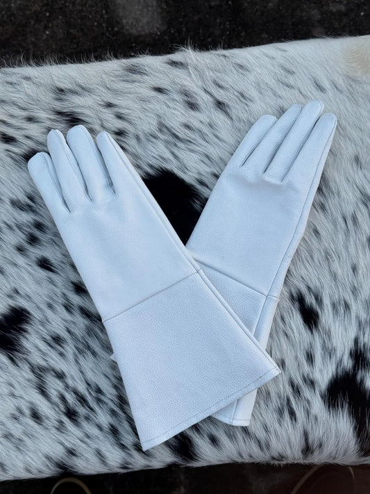 A pair of long white gloves laid flat on a black-and-white spotted faux fur surface.