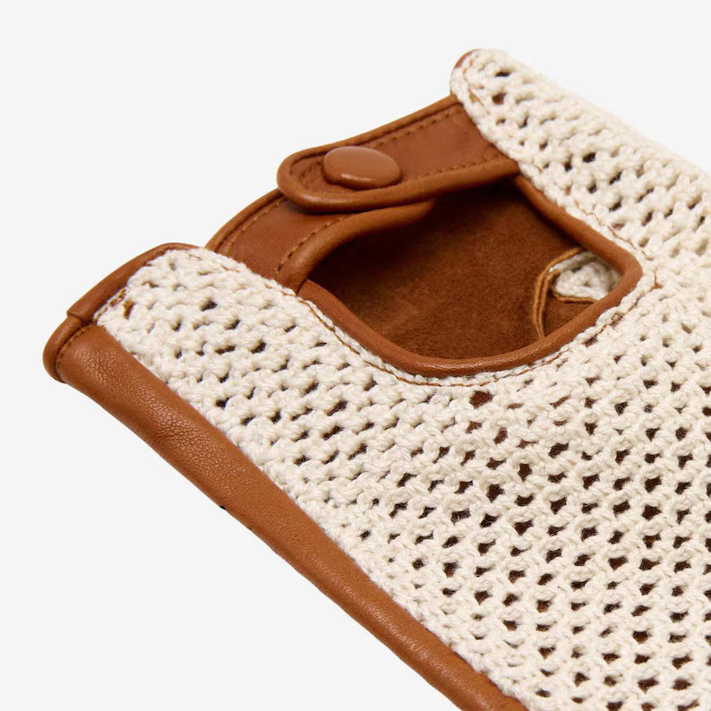Close-up of a crochet-patterned phone case with brown leather accents on a white background
