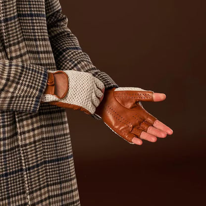 Person wearing a plaid coat with one brown leather glove and one white textured glove on a dark background