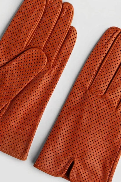 A pair of perforated leather gloves in a warm rust-orange color, arranged diagonally on a light gray background.