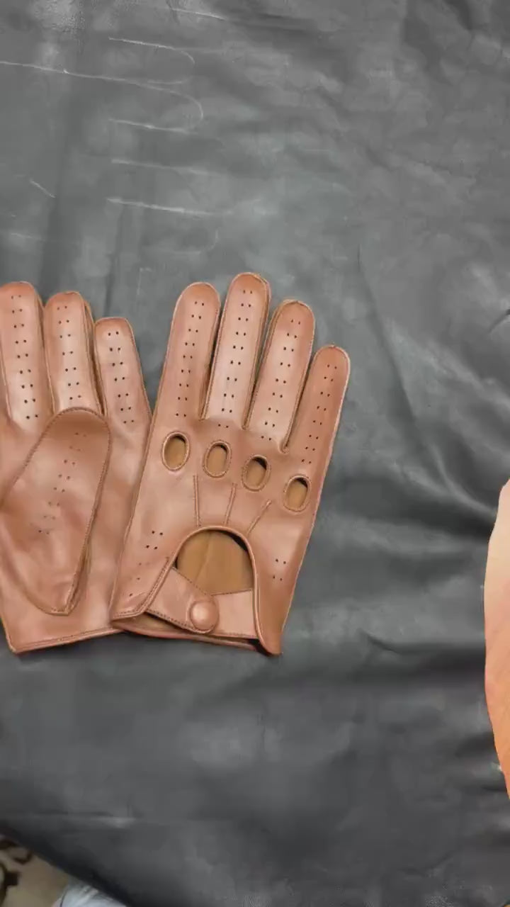 video of A pair of brown leather driving gloves with perforated ventilation holes and button closures, displayed on a clean white background.