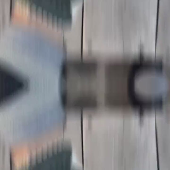 video of A pair of dark green leather gloves with white knit trim and textured white grip panels on the palms, shown being worn with a gray knit cuff and black jacket sleeve against a cobblestone pavement background.