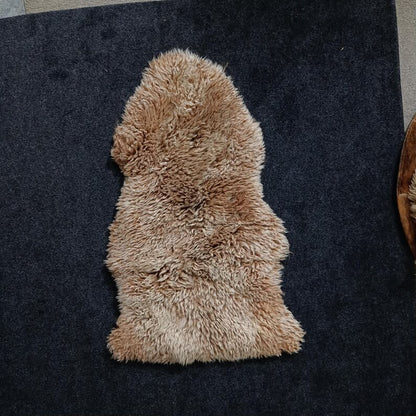 Sandy brown sheepskin pelt rug showing its natural shape and wool texture