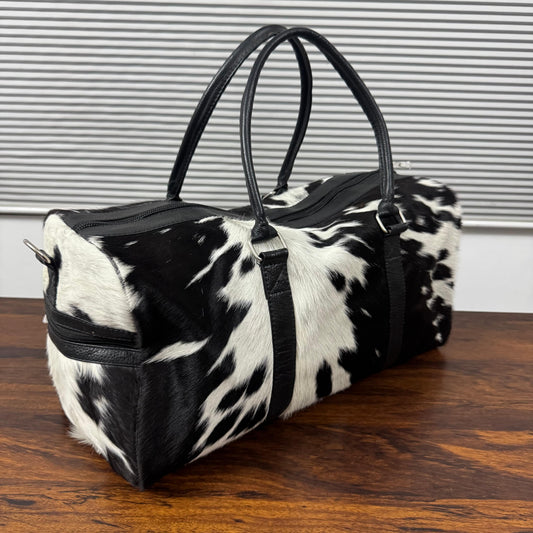 Black and white spotted cowhide duffel bag angled view