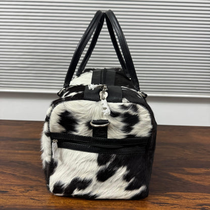 Black and white cowhide duffel bag with exterior end pocket