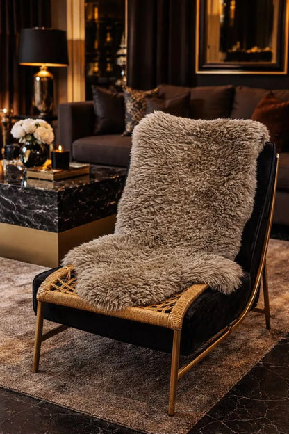 Taupe sheepskin rug styled over a black accent chair in a luxury living room