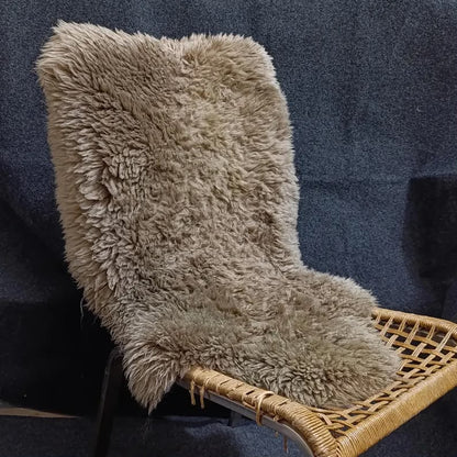 Taupe single pelt sheepskin rug displayed on a woven lounge chair