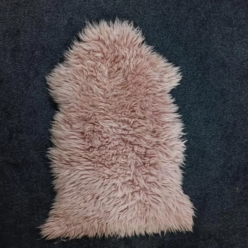 Warm pink natural sheepskin rug showing its soft wool texture and natural shape